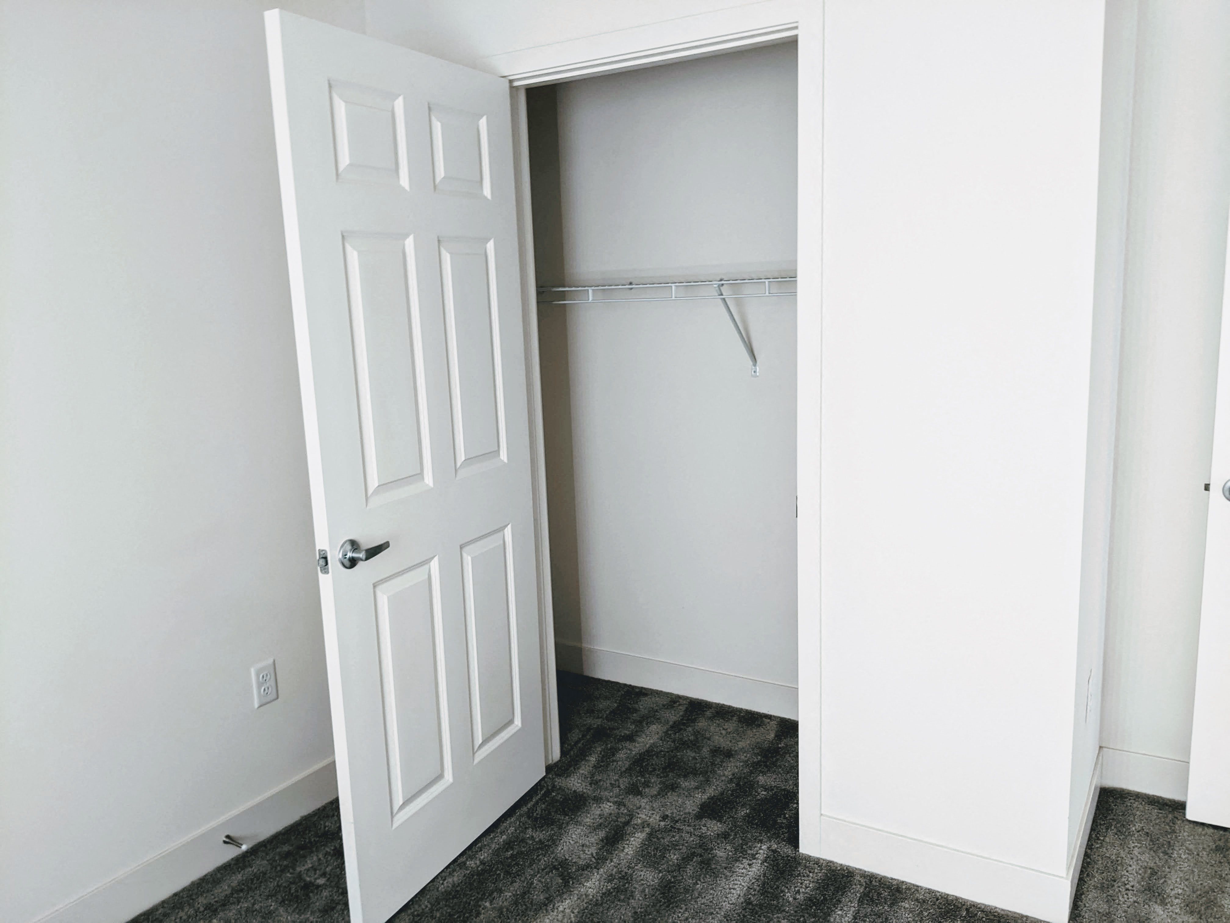 A closet with wire shelf and hanging rod